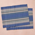 Two placemats laid flat (pink bg): "Set of two blue, gray, and white striped handloomed cotton placemats, handcrafted in Nepal by Ten Thousand Villages artisans