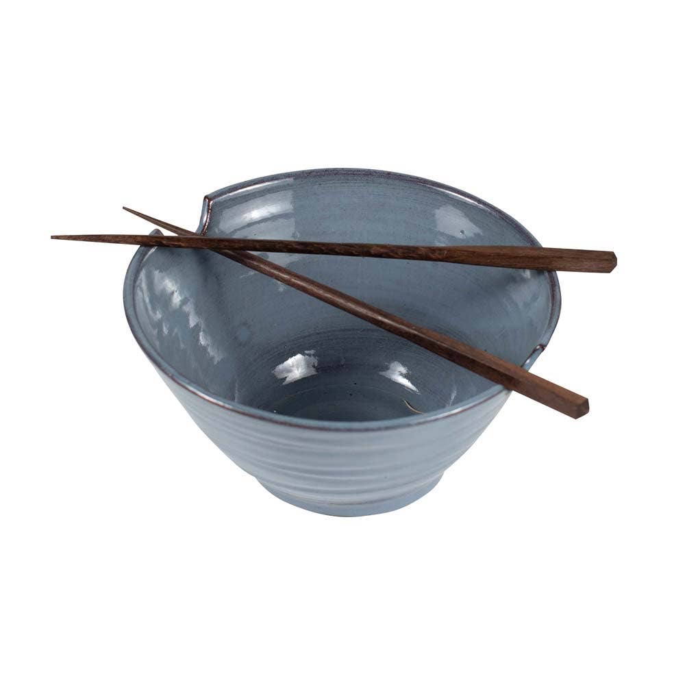 Bowl with chopsticks resting in grooves (white bg): "Blue glazed stoneware ramen bowl with Saj wood chopsticks resting in built-in rim grooves, handcrafted in Nepal"
