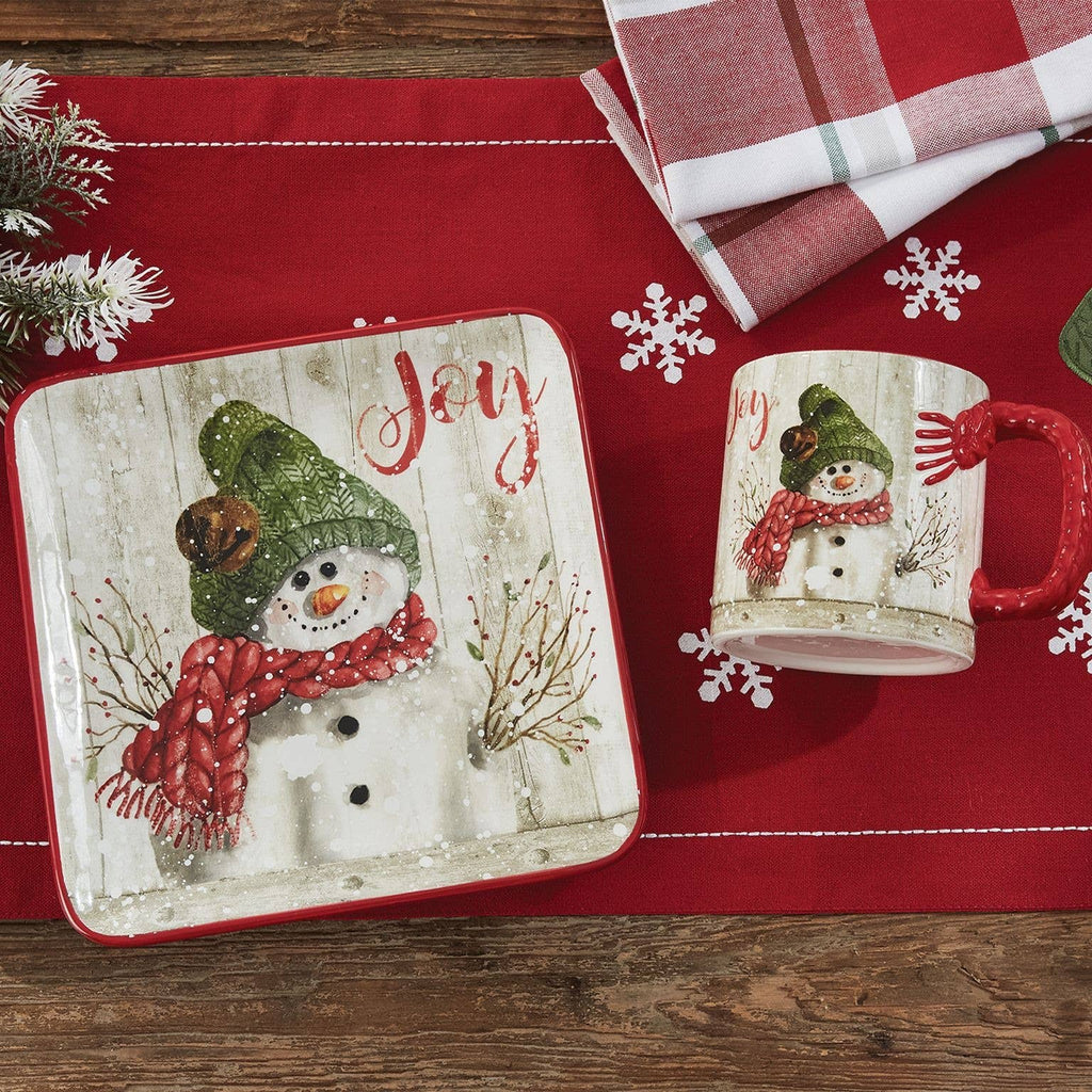 Park Designs Farmhouse Snowman salad plate styled on a red holiday table runner with matching Joy snowman mug, snowflake accents, and plaid napkin"
