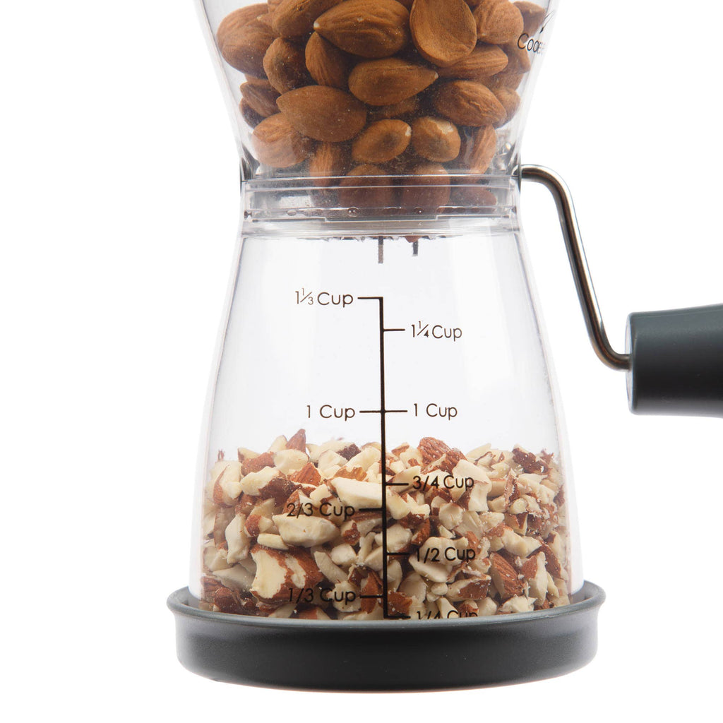 Close-up of the Progressive nut chopper filled with whole almonds in the upper chamber and coarsely chopped nuts collected in the lower measuring chamber.