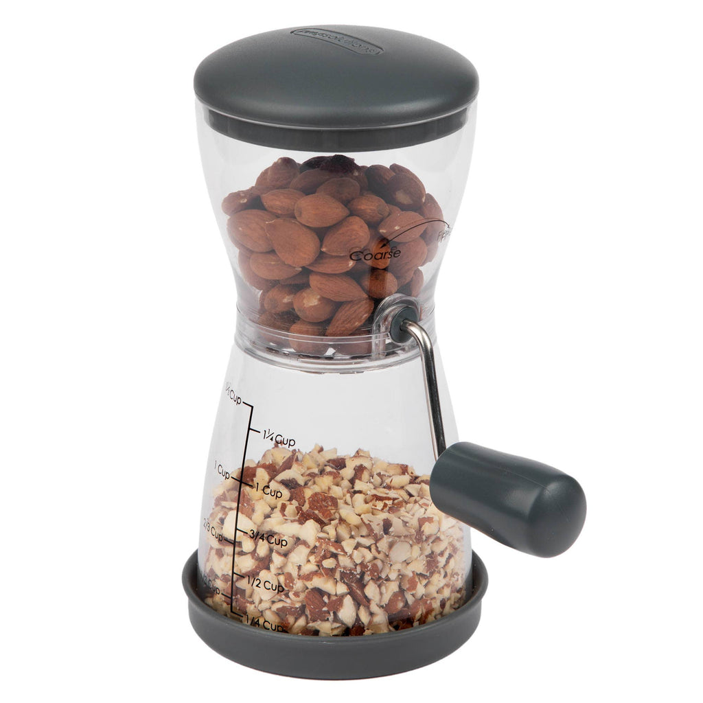 Progressive nut chopper filled with whole hazelnuts in the upper chamber and freshly chopped nuts in the lower collection chamber, shown on a white background.