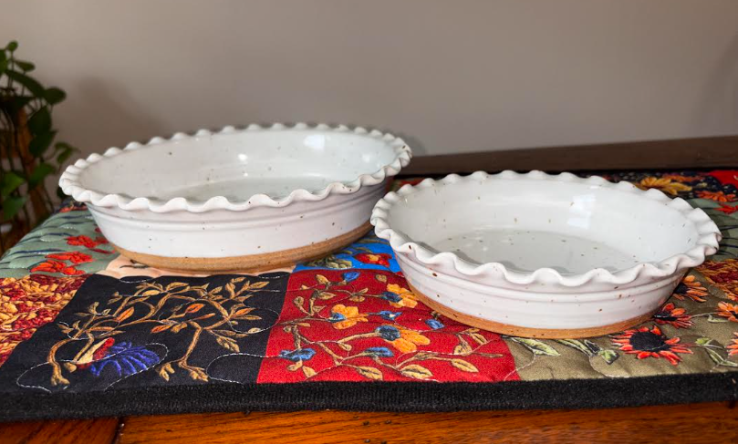 Side-by-side comparison of 9-inch and 6-inch hand-thrown white speckled stoneware deep dish pie plates with ruffled scalloped edges