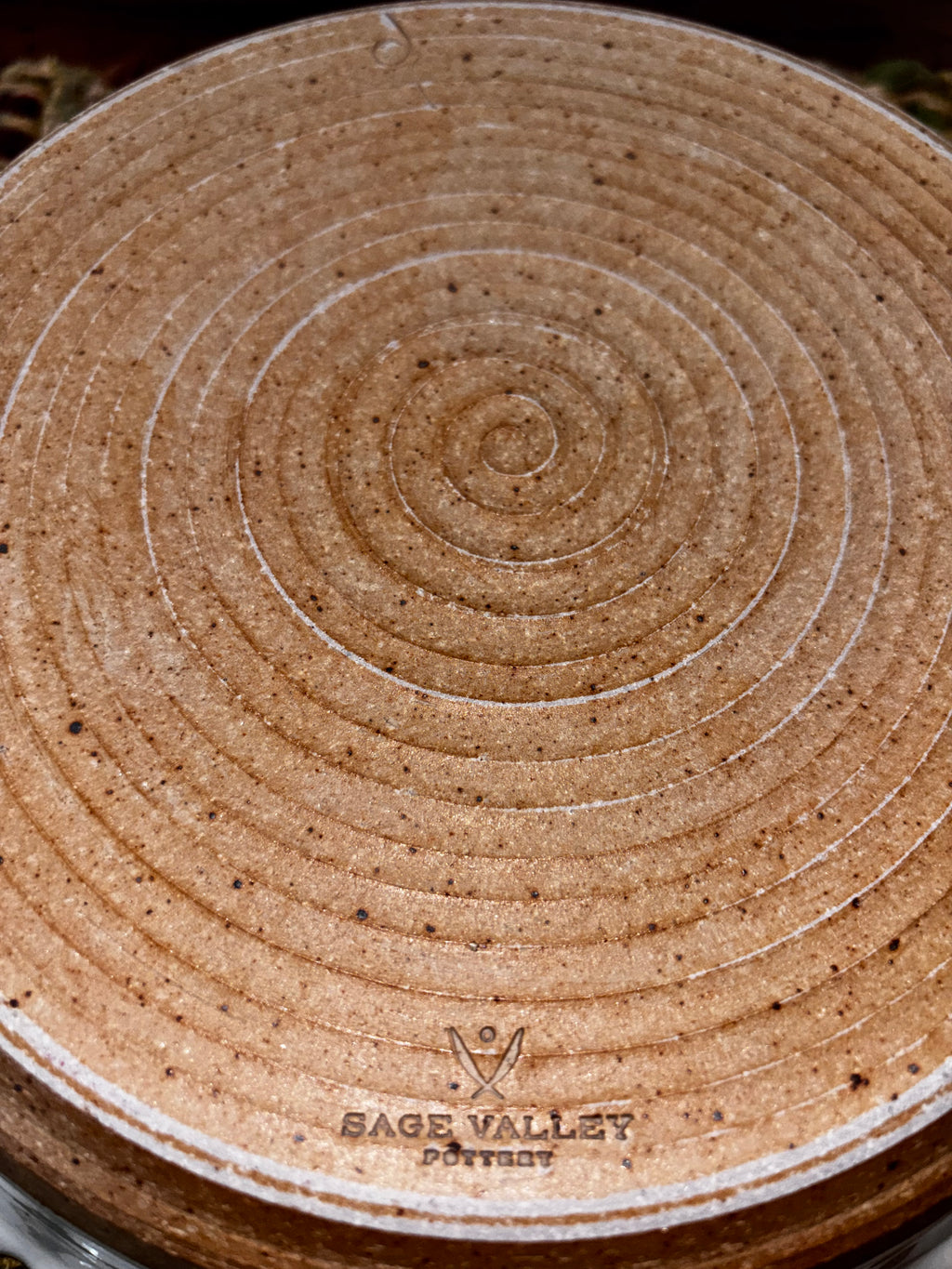 bottom of 9", Sage Valley Pottery stamp visible) Unglazed natural clay base of a 9-inch Sage Valley Pottery deep dish pie plate showing hand-thrown spiral rings and stamped maker's mark