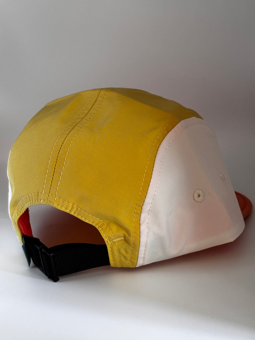  "Back view of Landmark Project Landmark Hike Hat showing yellow, white, and orange colorblock panels with black nylon strap closure"