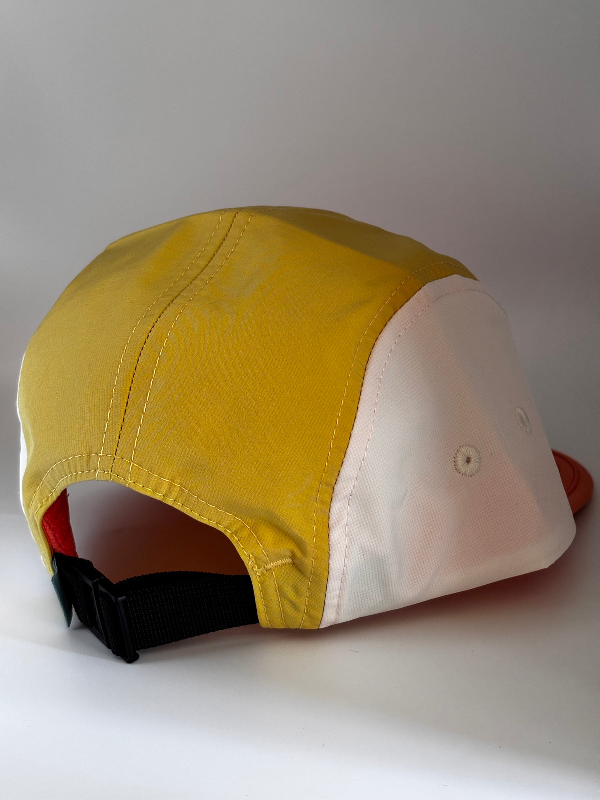  "Back view of Landmark Project Landmark Hike Hat showing yellow, white, and orange colorblock panels with black nylon strap closure"