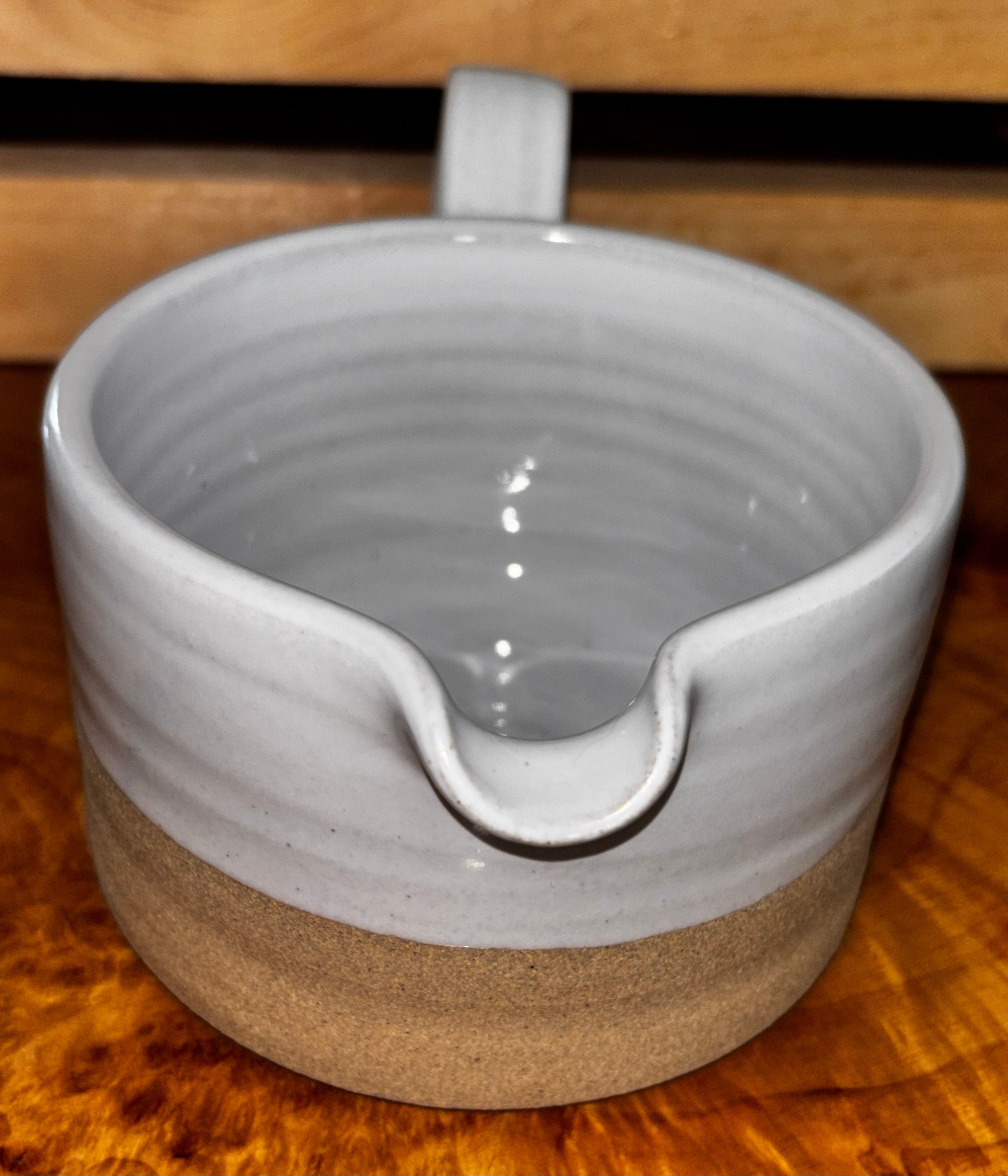 Top-down interior view on live edge wood → "Overhead view of Farmhouse Pottery Silo stoneware gravy boat showing the smooth white glazed interior with hand-thrown spiral, displayed on a live edge wood surface"