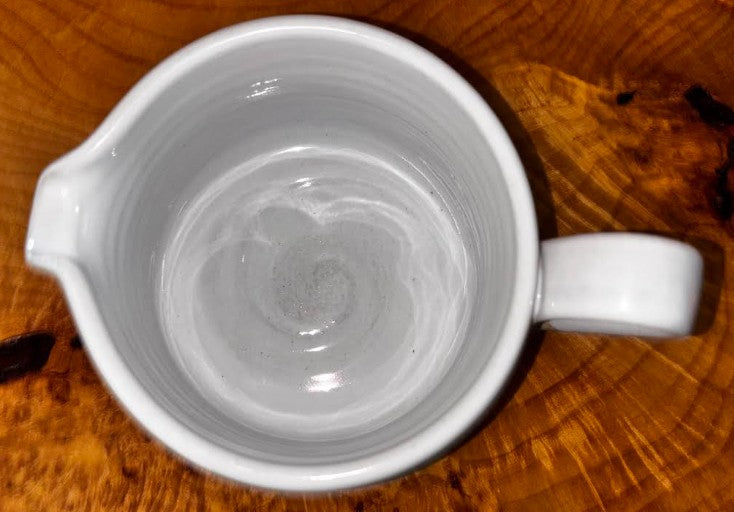 "Overhead view of Farmhouse Pottery Silo stoneware gravy boat showing the smooth white glazed interior with hand-thrown spiral detail, displayed on a live edge wood surface"