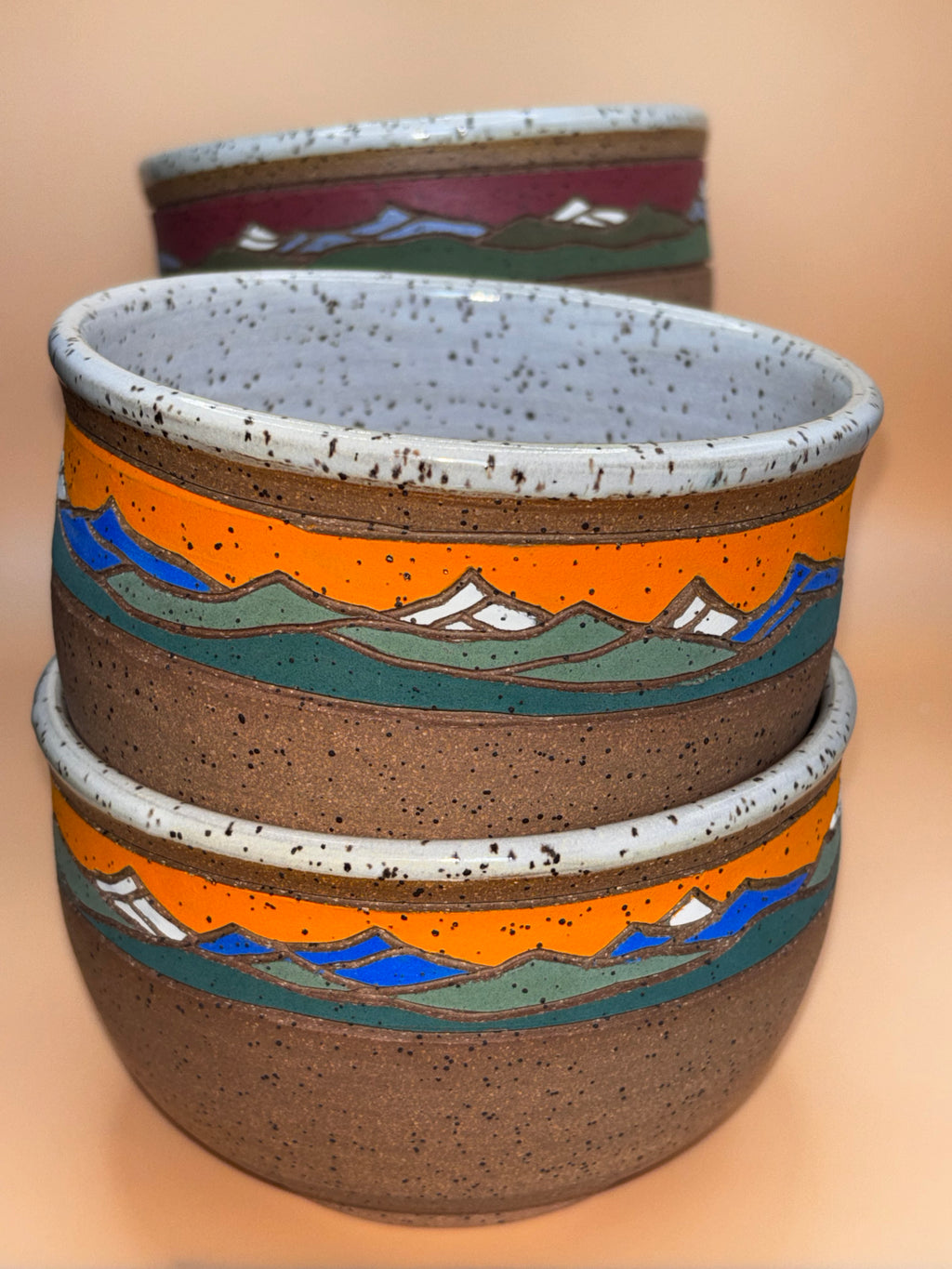 Sunset Peak set stacked (close, vivid orange & blue):

"Set of 2 handmade speckled stoneware bowls with vibrant orange sunset and blue mountain landscape band, stacked showing interior — Forest Jeannie Pottery"