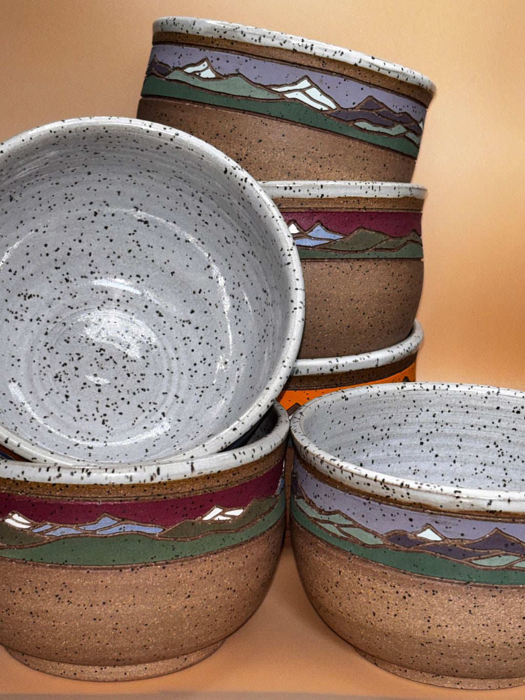 "All three colorways of Forest Jeannie handmade speckled stoneware mountain landscape bowls stacked together, showing speckled white interiors — handmade pottery by Forest Jeannie"
