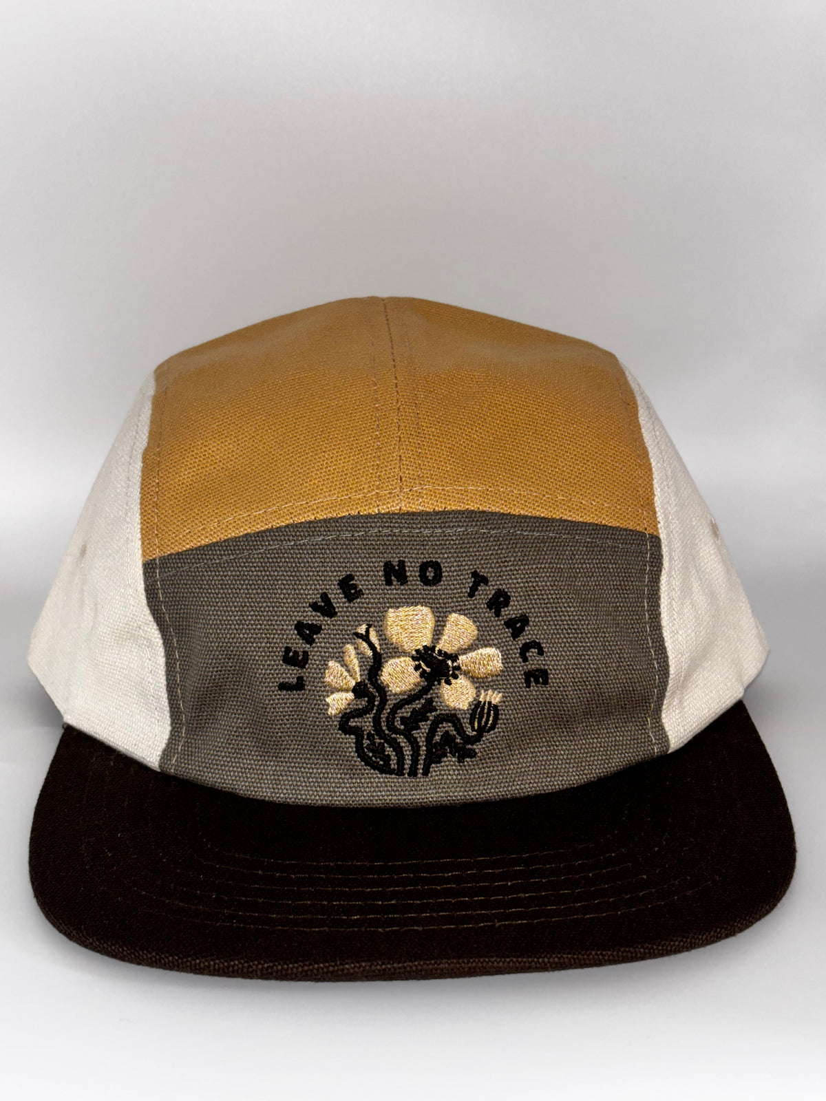  "Landmark Project Leave No Trace Camp Hat in tan, gray, and cream colorblock organic cotton with embroidered Leave No Trace floral logo on front panel, black brim"