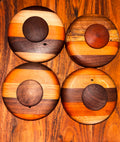 Four handmade extra-large cathead biscuit cutters displayed top-down on a warm wood surface, each featuring a striped mixed-wood base in walnut, maple, and cherry tones with a rounded dark wood center knob 