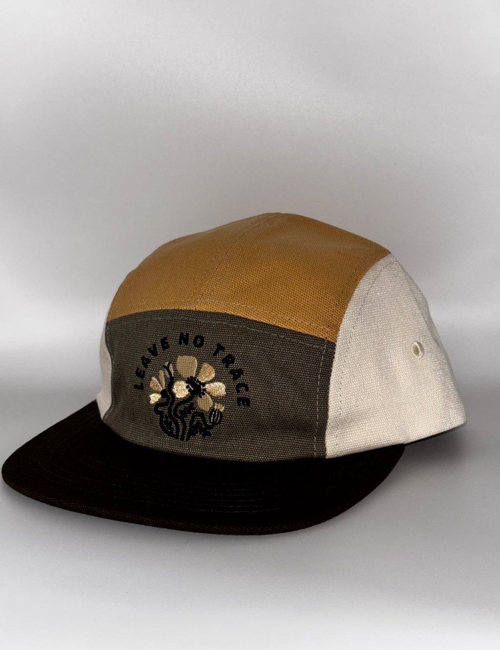  "Landmark Project Leave No Trace Camp Hat in tan, gray, and cream colorblock organic cotton, 3/4 side angle showing Leave No Trace floral embroidery and black brim"