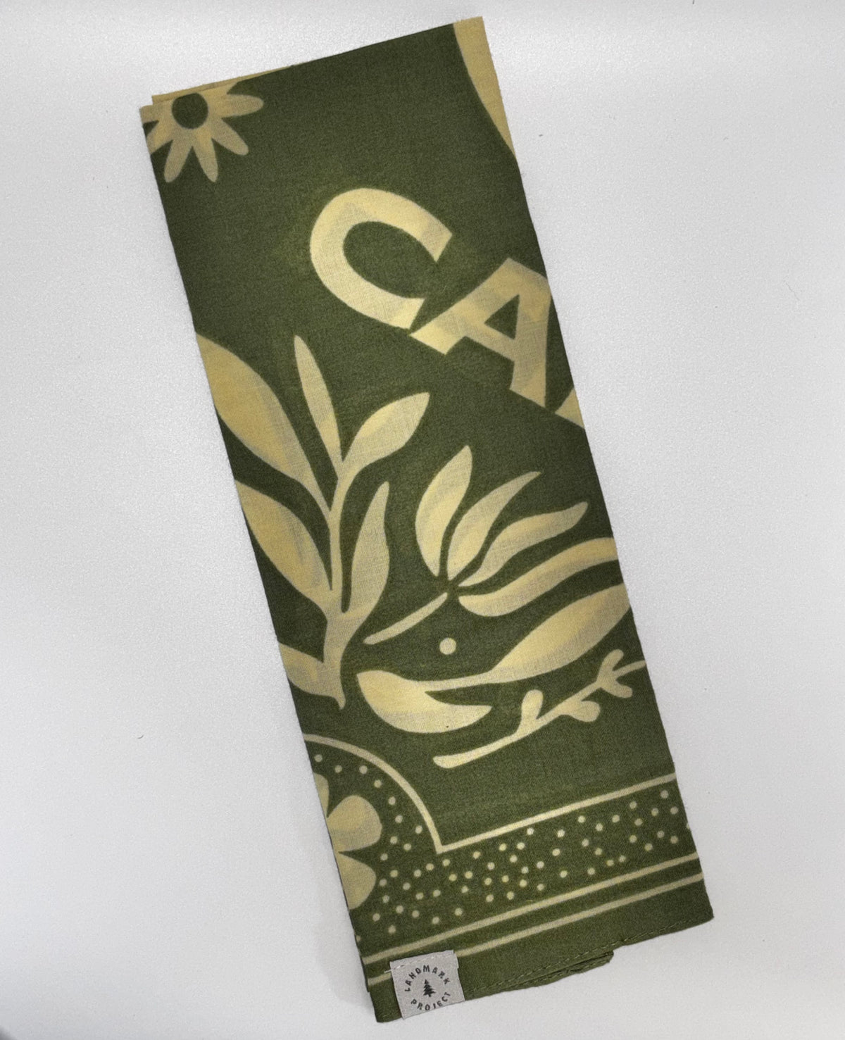 Woodsy Owl Bandana folded): "Landmark Project Woodsy Owl Bandana folded showing olive green BCI cotton with cream botanical leaf, Owl, and floral print with Landmark Project label"