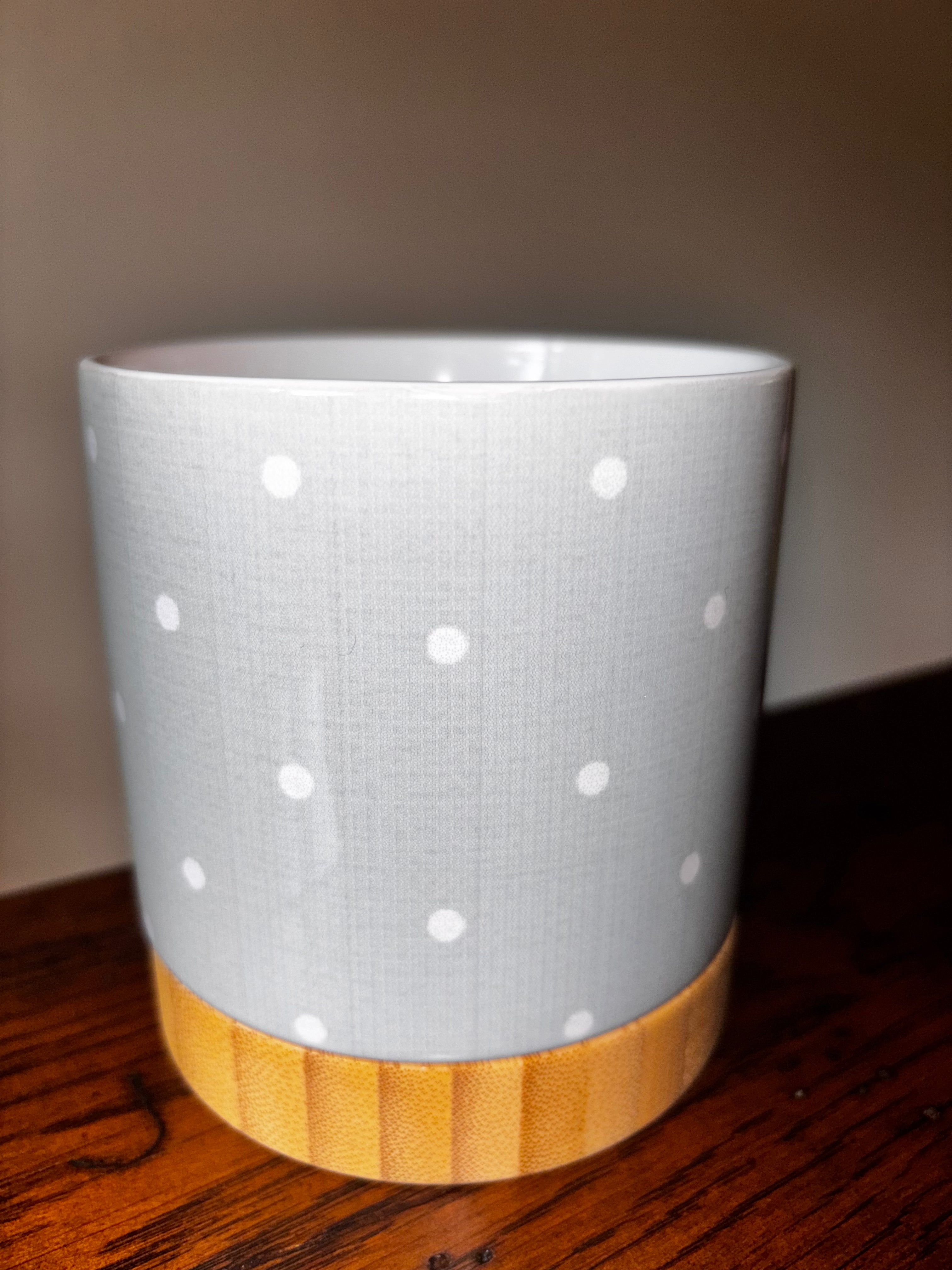 Light grey ceramic polka dot planter with natural bamboo tray base, close-up view