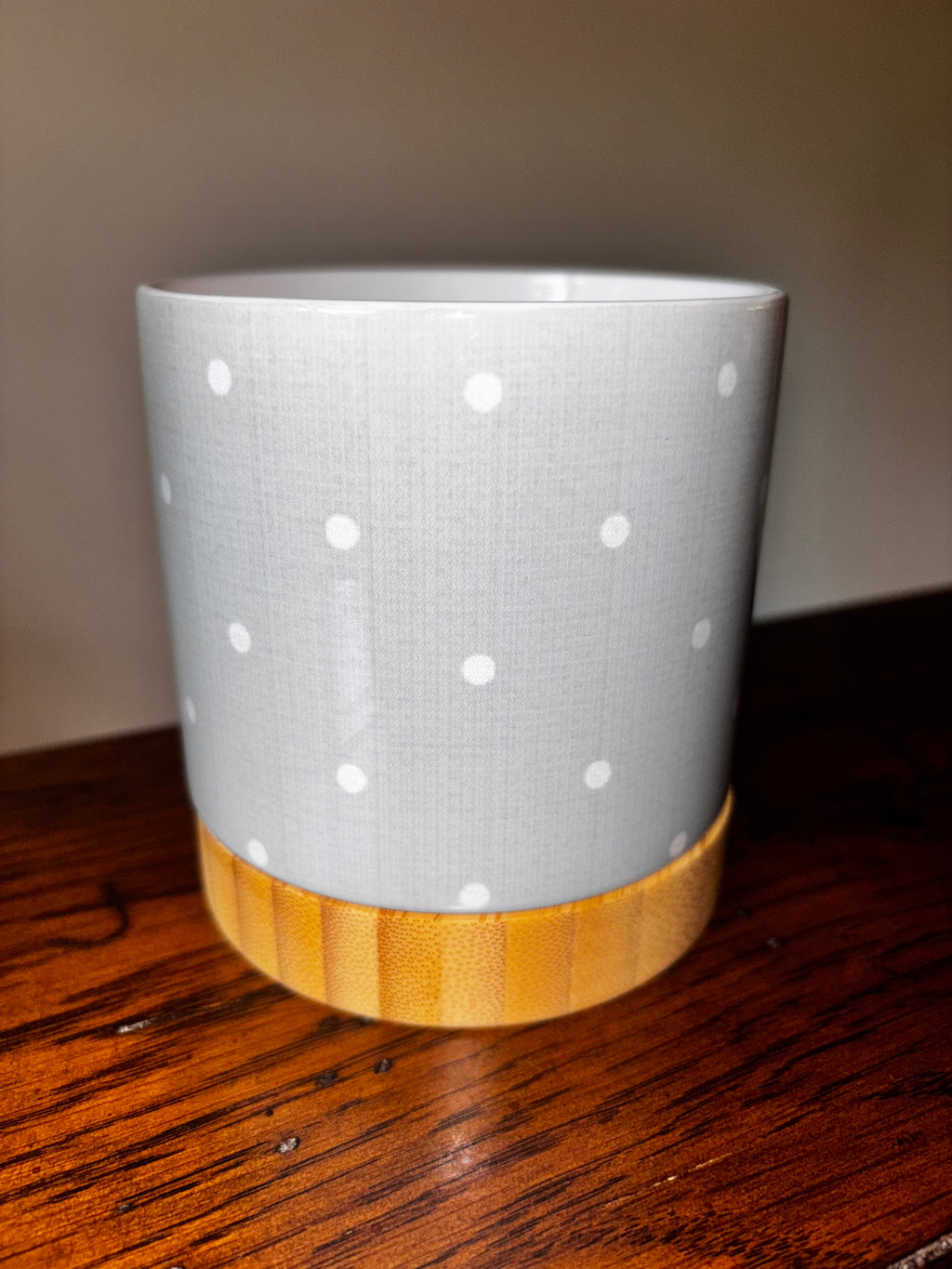 Light grey ceramic polka dot planter with natural bamboo tray base, close-up view