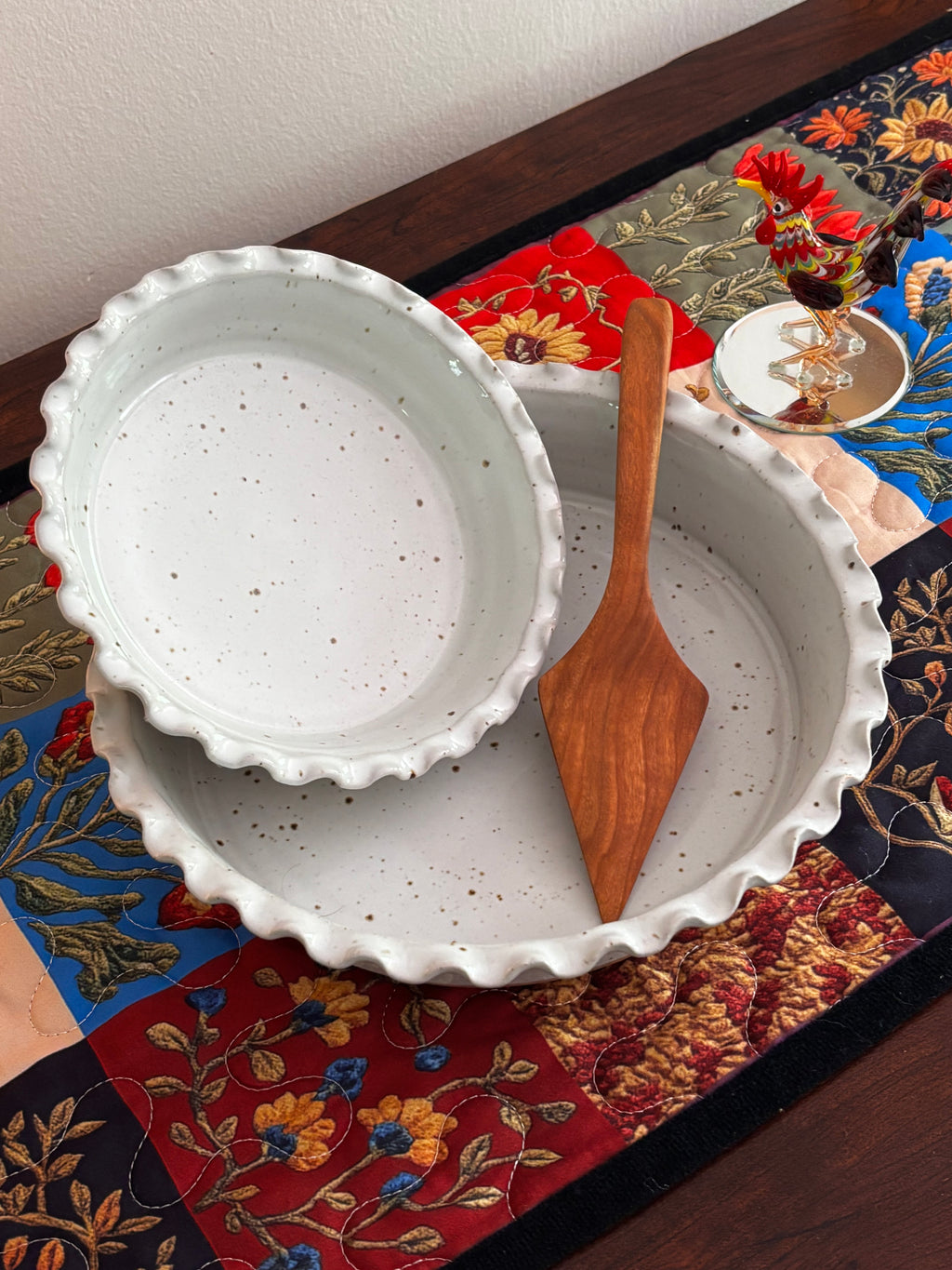 Sage Valley Pottery speckled white stoneware pie plate set with handmade West Virginia hardwood pie server, styled on a colorful patchwork table runner