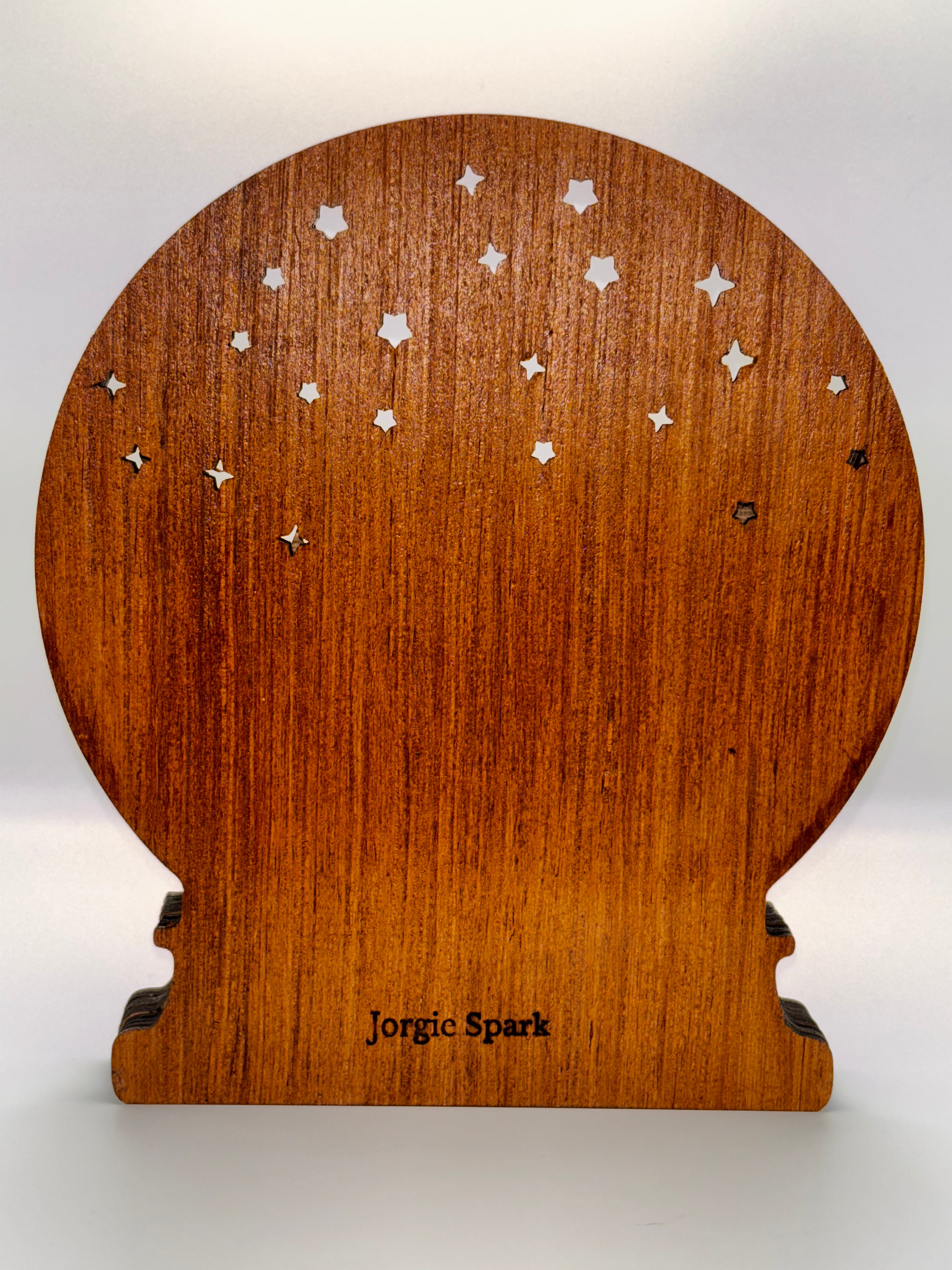 Back of the Winter Deer wooden snowglobe showing warm wood grain, star-shaped cutouts, and the Jorgie Spark mark