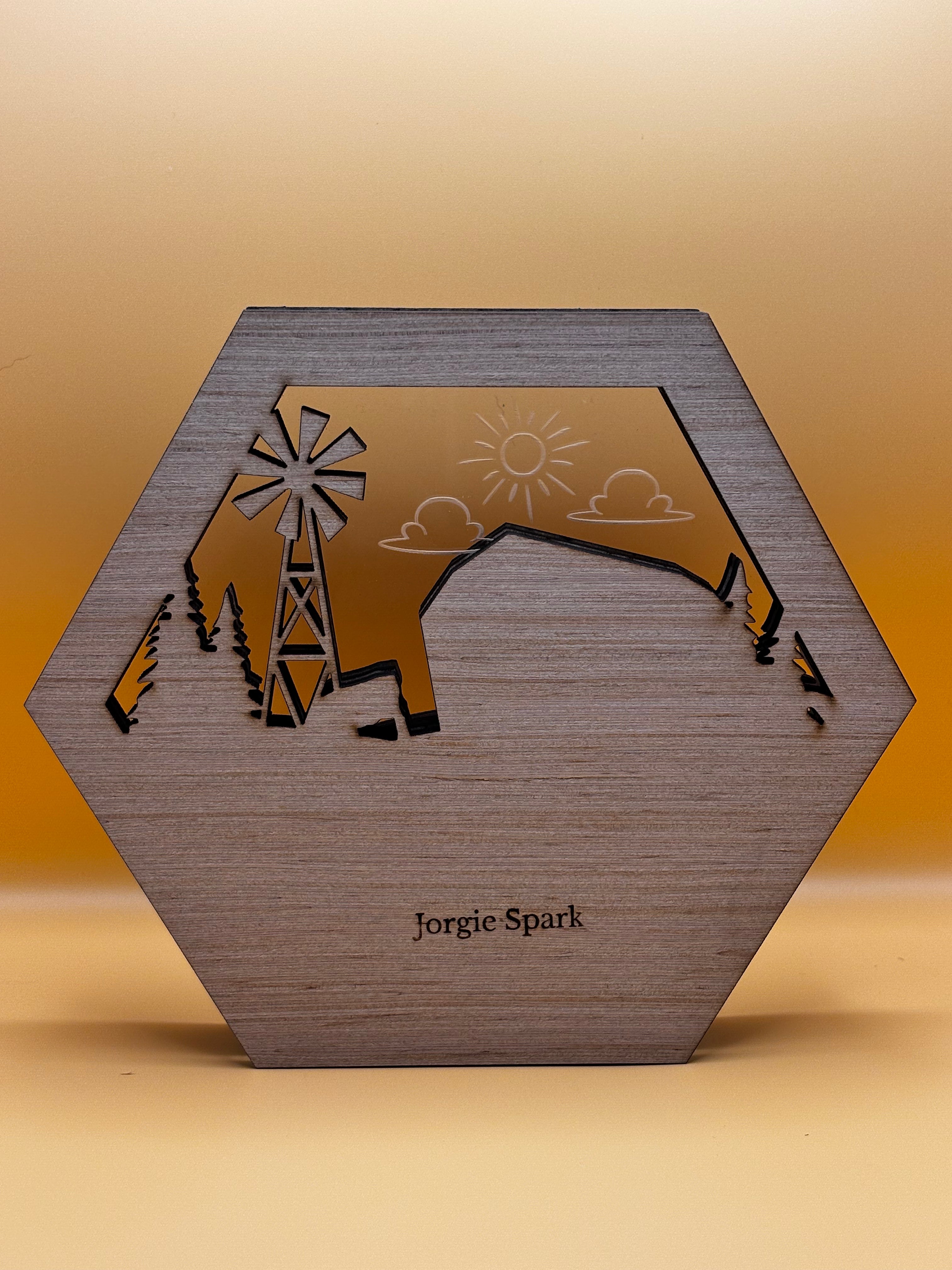 Back of the hexagonal farm artwork showing wood grain, the Jorgie Spark mark, and clear acrylic with an etched sun and clouds.