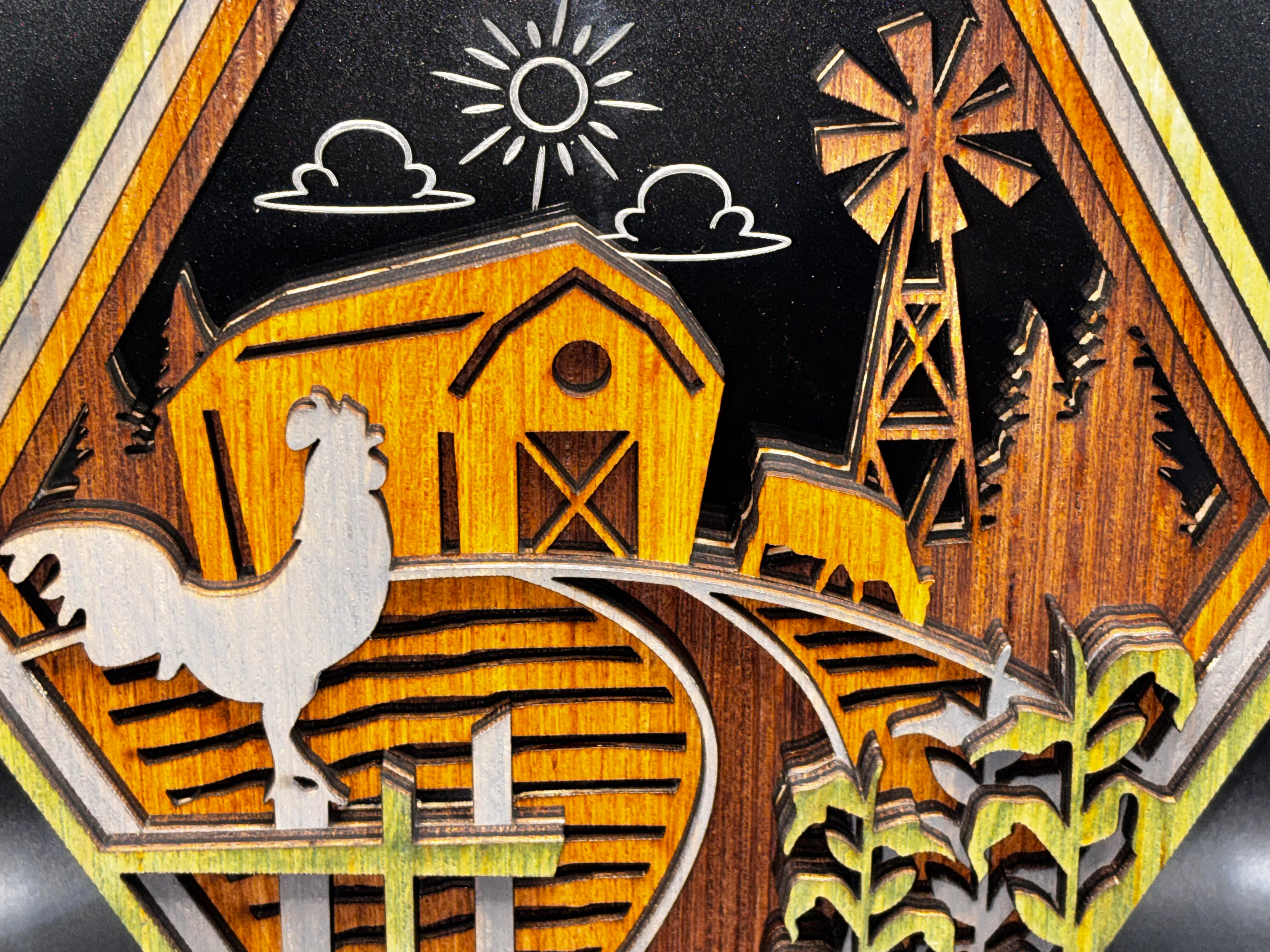 Close-up of the farm scene’s layered rooster, barn, cow, and windmill beneath a sun-and-cloud design etched into acrylic.