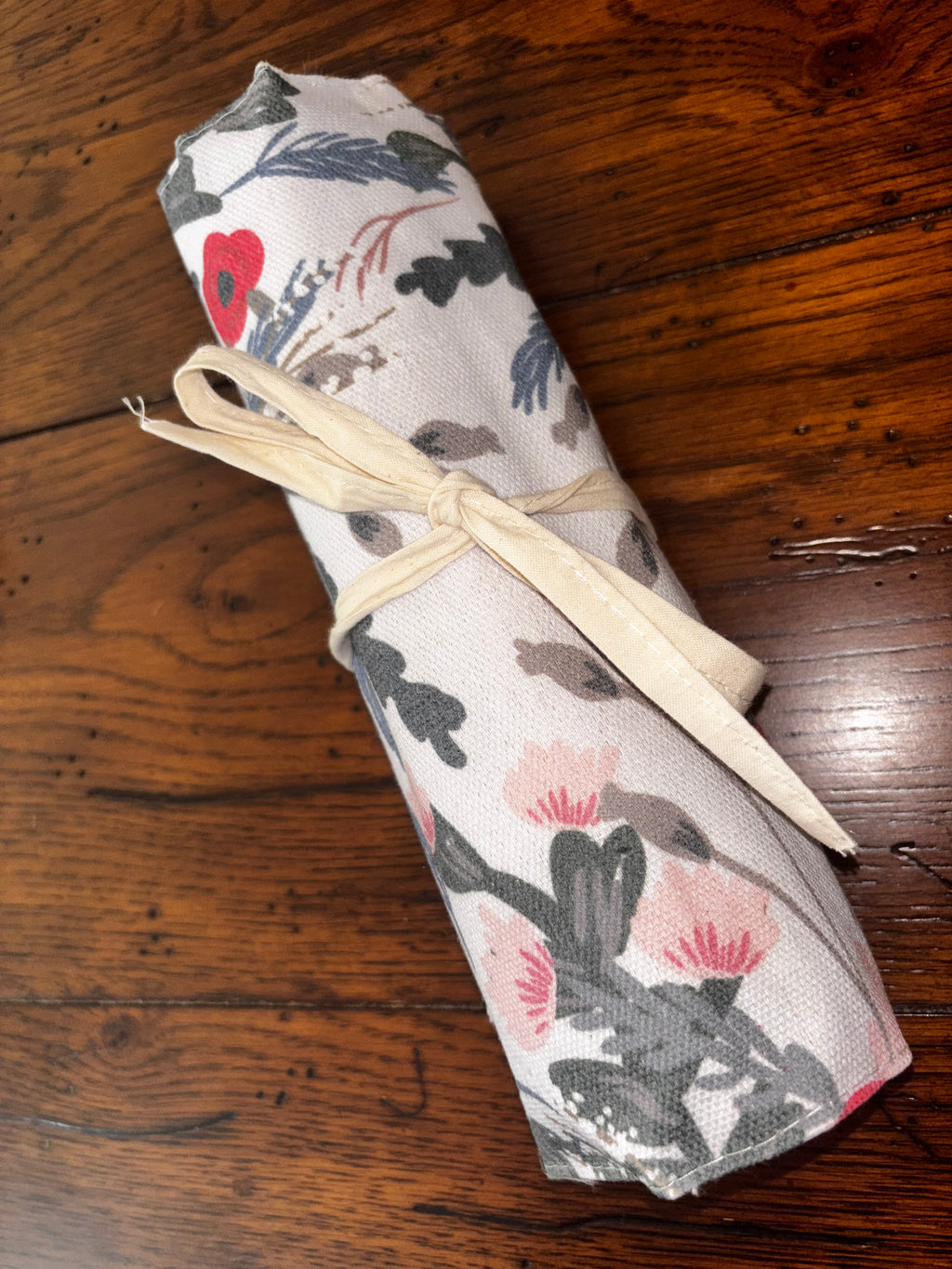 Floral cutlery holder rolled closed and secured with cream fabric ties.