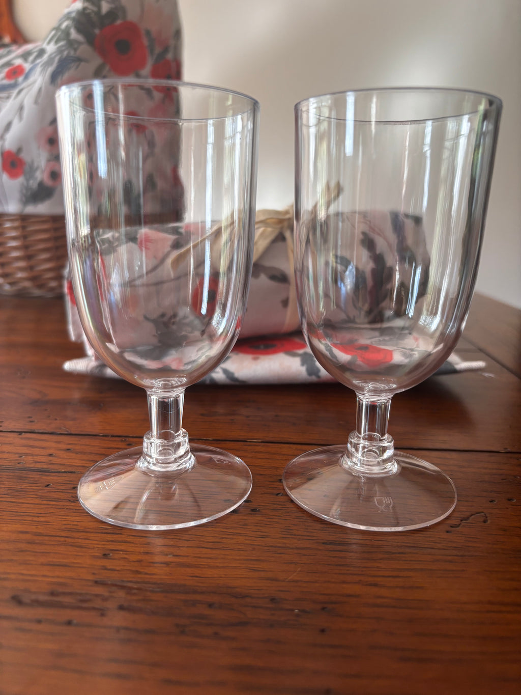 Close-up of the two included clear, short-stemmed drinking glasses with the floral picnic tote behind them.