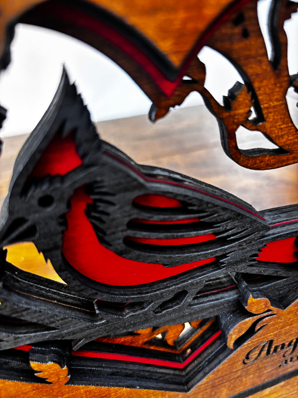 Angled close-up showing the raised wood layers of the cardinal’s wing, breast and heart-shaped border.