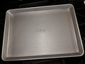 Angled view of the USA Pan half sheet pan with embossed center logo and continuous raised rim.