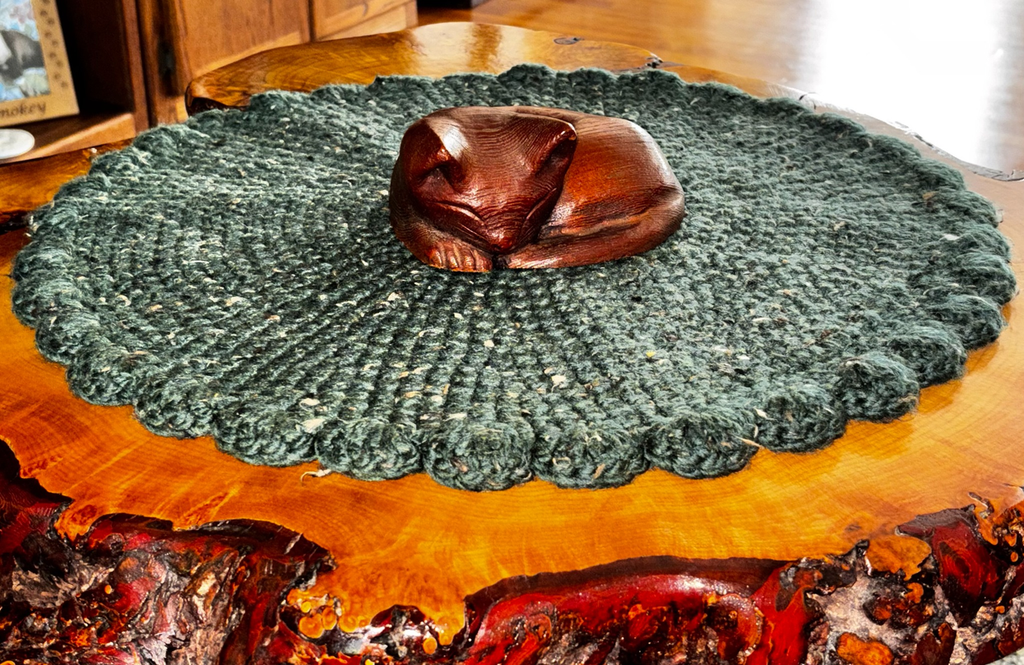 Deep green wool blend crochet cat lounger displayed to show its full round shape and rich earthy texture, handmade by Sleeping Whiskers Studio in Upstate New York.
