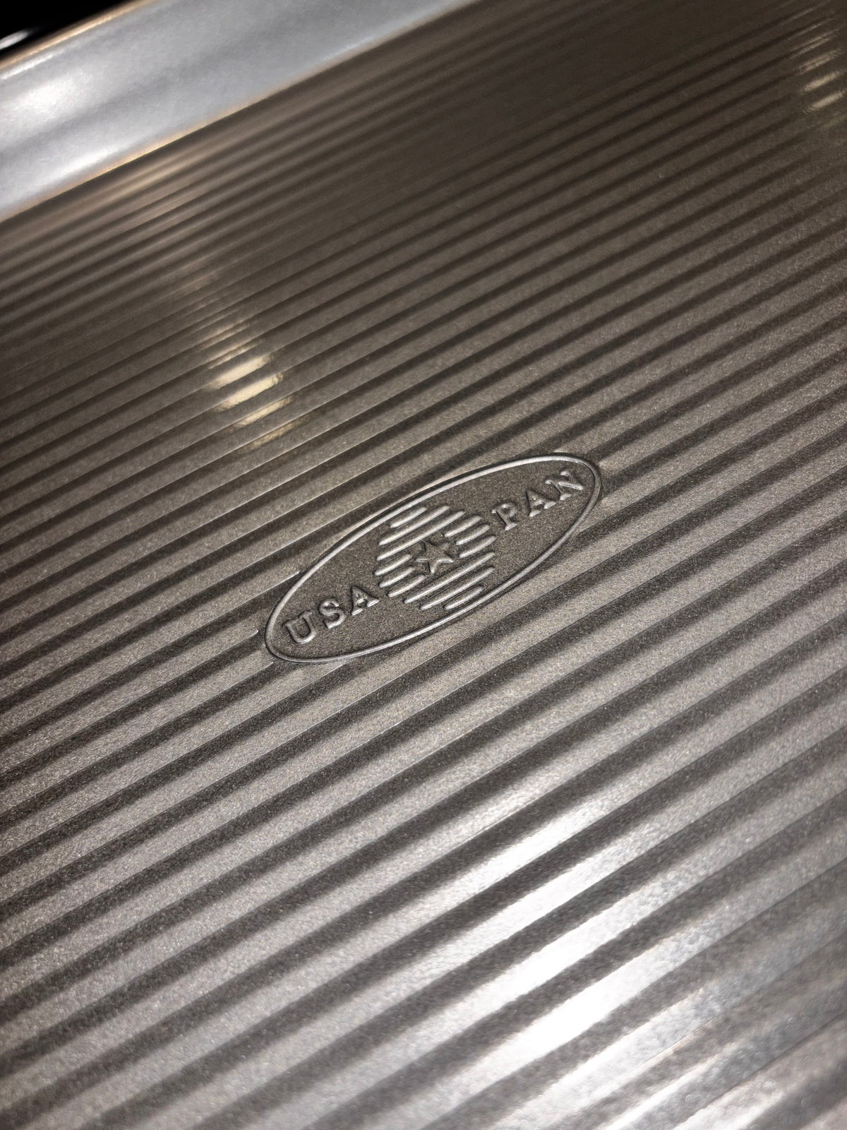 Close view of the USA Pan quarter sheet pan with rounded rim, corrugated surface and embossed USA Pan logo.
