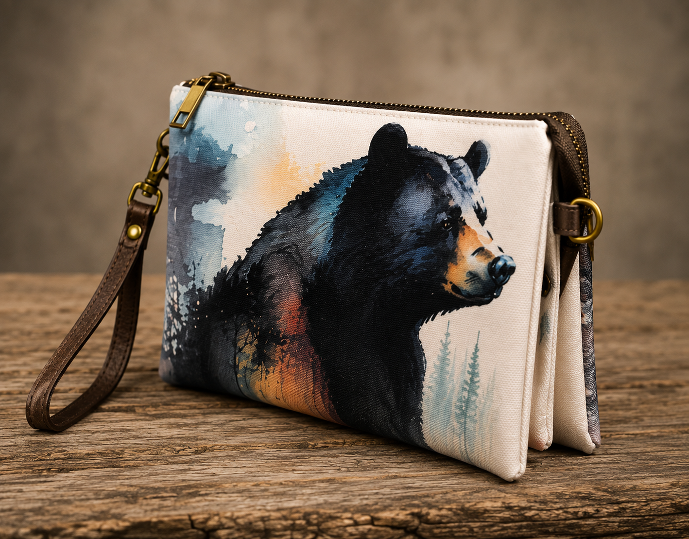 Angled view of canvas crossbody bag showing watercolor black bear wildlife art and wristlet strap detail, displayed on a rustic wood surface — Anngoti