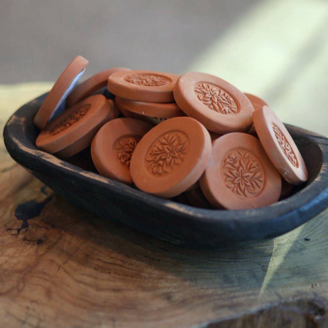 "Gravesco handmade terracotta brown sugar keepers with floral medallion design piled in a dark wooden dough bowl on rustic wood surface"