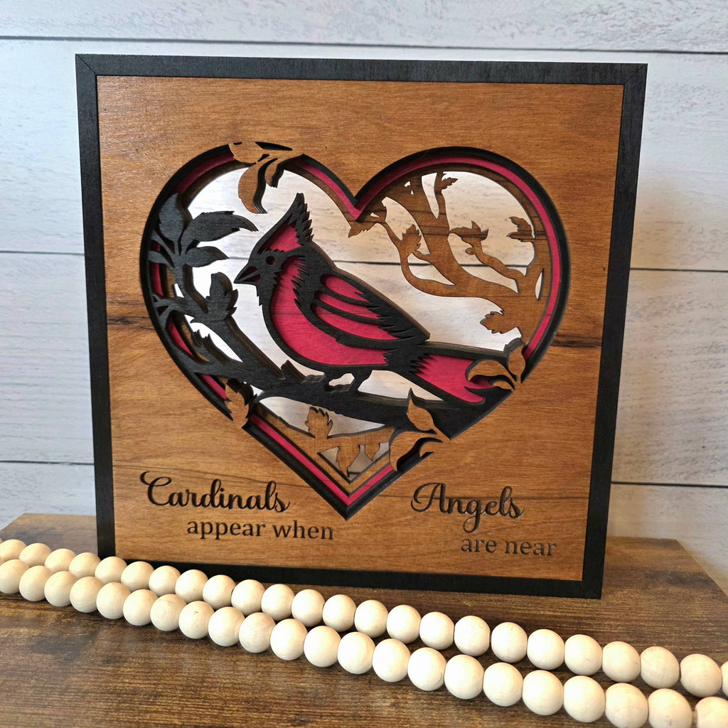 Front view of the cardinal heart layered wood plaque with its remembrance message, styled beside wooden beads.