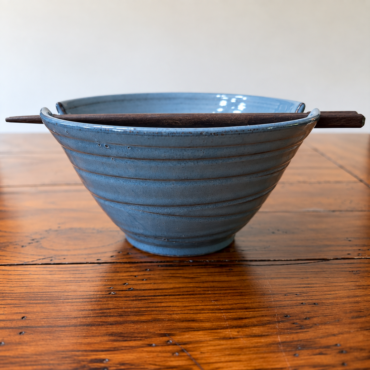 "Indigo Night handcrafted stoneware ramen bowl with notched rim and wooden chopsticks on white background — Ten Thousand Villages fair trade artisan piece — Ramen Night In Collection"