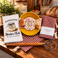 Overhead view of the sourdough accessory set with proofing basket, embosser, Starter Club towel, checked bread bags and Danish dough whisk.
