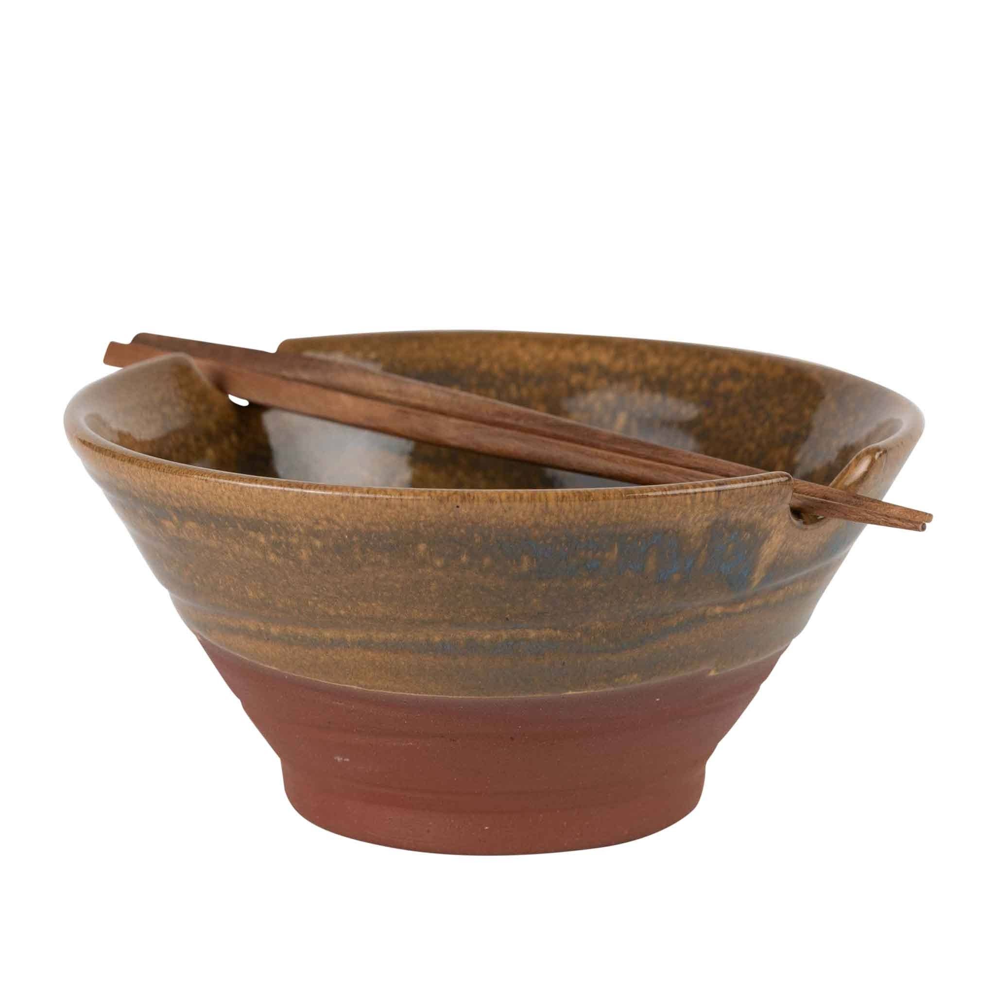 Bowl with chopsticks resting in notches (white bg, angled): "Handmade terracotta and amber glazed ceramic ramen bowl with Saj wood chopsticks resting in brim notches, handcrafted in Nepal by Ten Thousand Villages"
