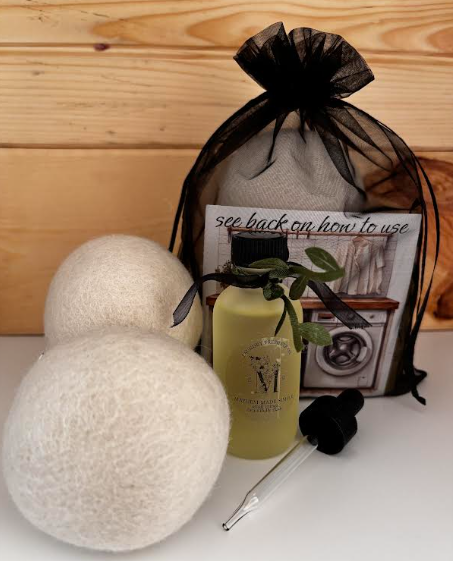 Two white wool dryer balls with Cedar Orchard laundry scent oil, glass dropper, instruction card, and black drawstring gift bag.