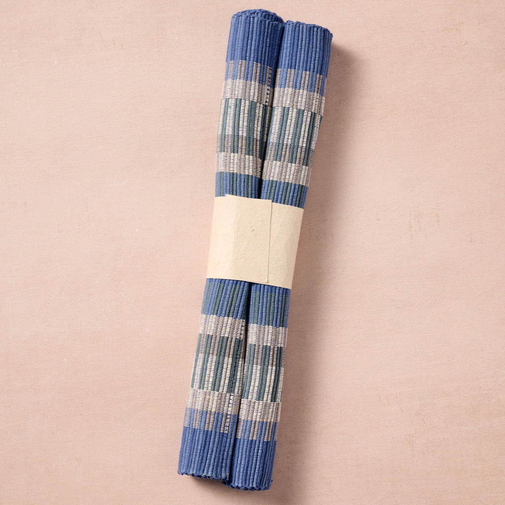 Two mats rolled and banded (pink bg): "Two blue striped handloomed cotton placemats rolled and banded, ready to gift, handcrafted in Nepal"