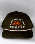 An olive green baseball cap with white embroidered text reading 'FIND ME IN THE FOREST' and an orange leaf design on the front, plus a white rope detail across the brim, shown against a neutral gray background.