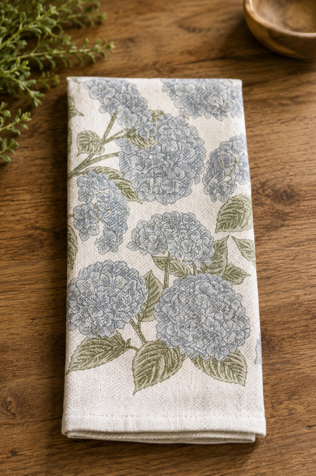 Hydrangea Towel — "Southern Fried Design Barn screen printed hydrangea kitchen towel folded on wood surface, cream cotton with blue hydrangea and green leaf screen print design"