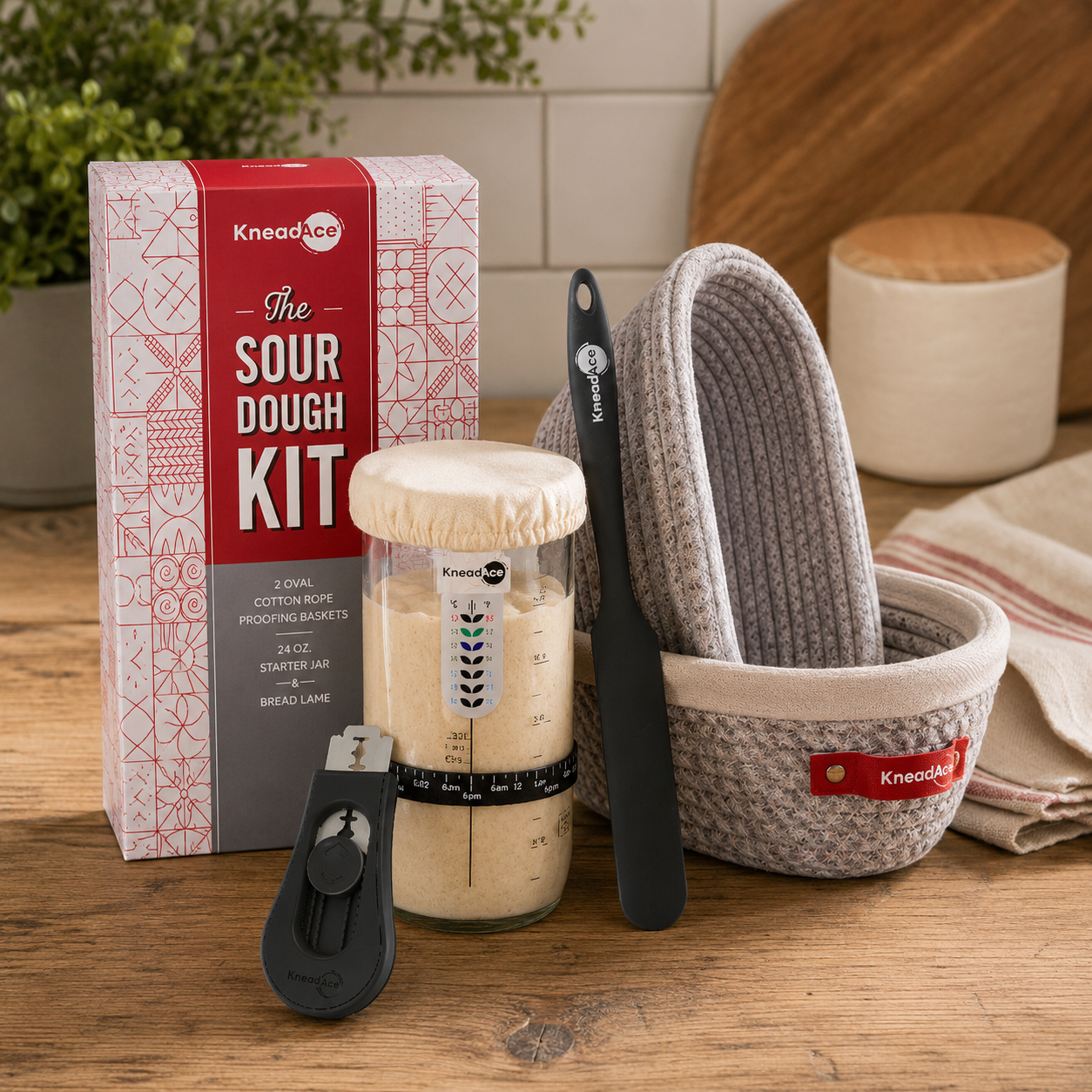 KneadAce Kit — "KneadAce Artisan Sourdough Kit displayed on wood surface with glass starter jar, bread lame, oval cotton rope banneton proofing baskets, and product box"