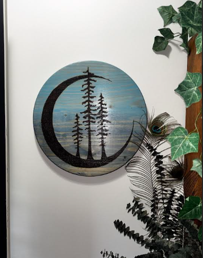 Tres Luna crescent moon and pine tree wood burn wall art displayed on white wall with trailing ivy and fern — Adirondack Art Co."