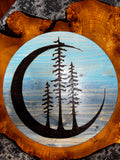 "Close-up of Tres Luna handcrafted wood wall art showing crescent moon and three pine trees on blue-painted pine, with natural live edge surround — Adirondack Art Co."