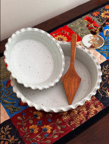 Sage Valley Pottery speckled white stoneware pie plate set with handmade West Virginia hardwood pie server, styled on a colorful patchwork table runner