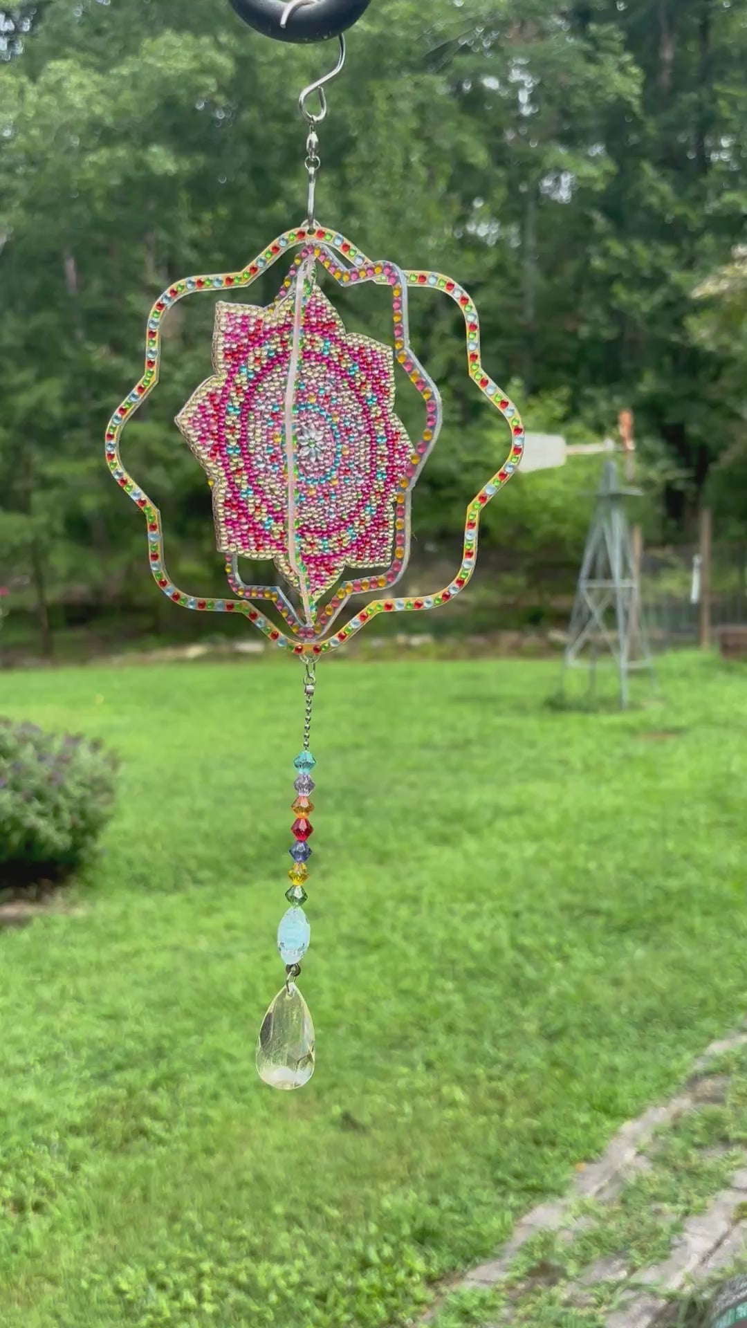 Handcrafted mandala sun catcher and wind spinner spinning in natural light, showing colorful rainbow reflections dancing across the room — by Sleeping Whiskers Studio
