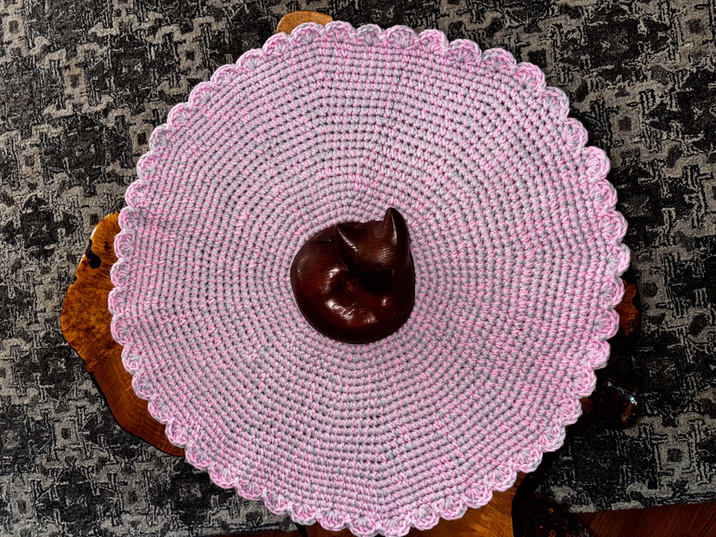 Large round pink and gray crochet cat lounger displayed flat, showing the generous 25-inch size and handcrafted texture by Sleeping Whiskers Studio.