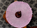 Large round pink and gray crochet cat lounger displayed flat, showing the generous 25-inch size and handcrafted texture by Sleeping Whiskers Studio.