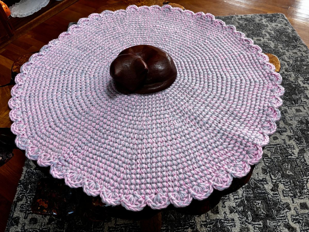 Side view of the large pink and gray crochet cat lounger showing the thick, soft hand-crocheted construction and scalloped edge detail.