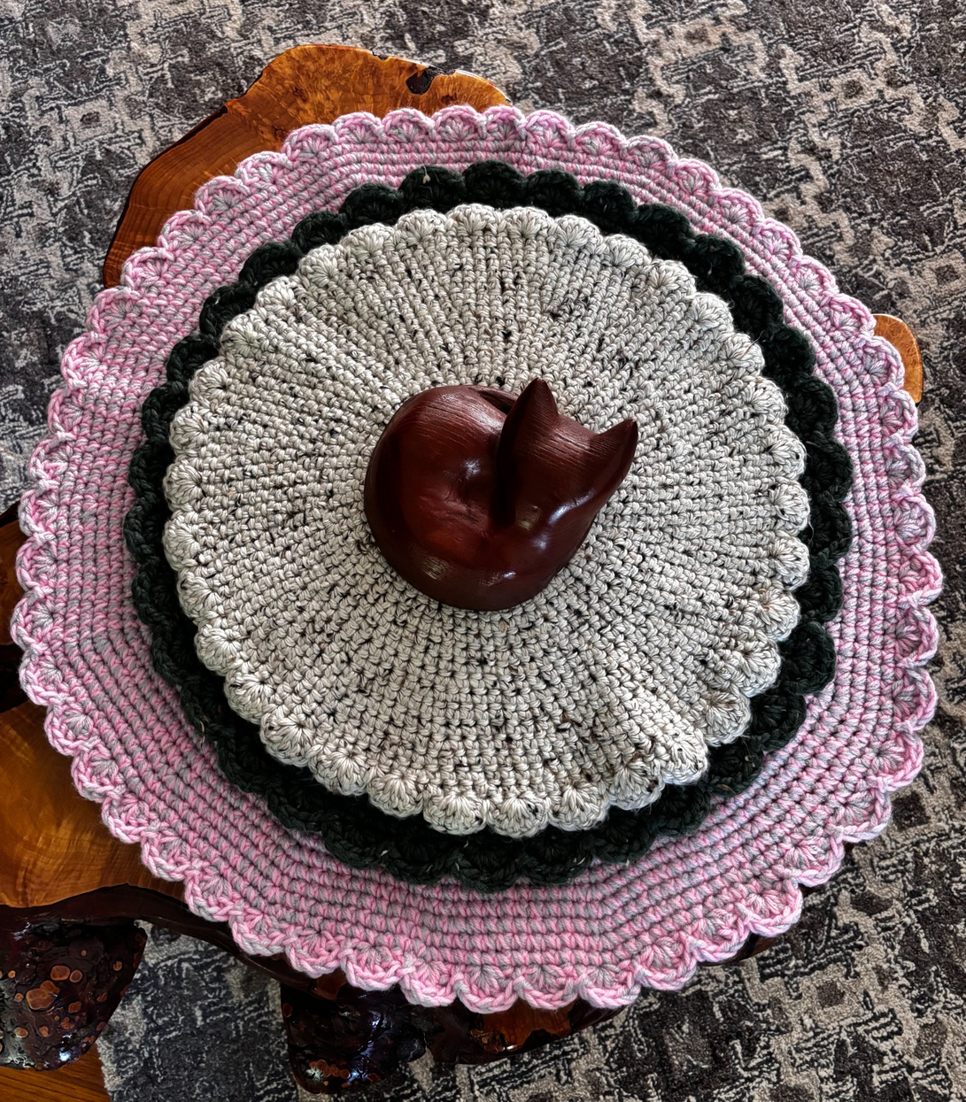 Three handcrafted crochet cat loungers displayed together, showing the pink and gray, deep green wool blend, and natural tweed wool blend styles by Sleeping Whiskers Studio.