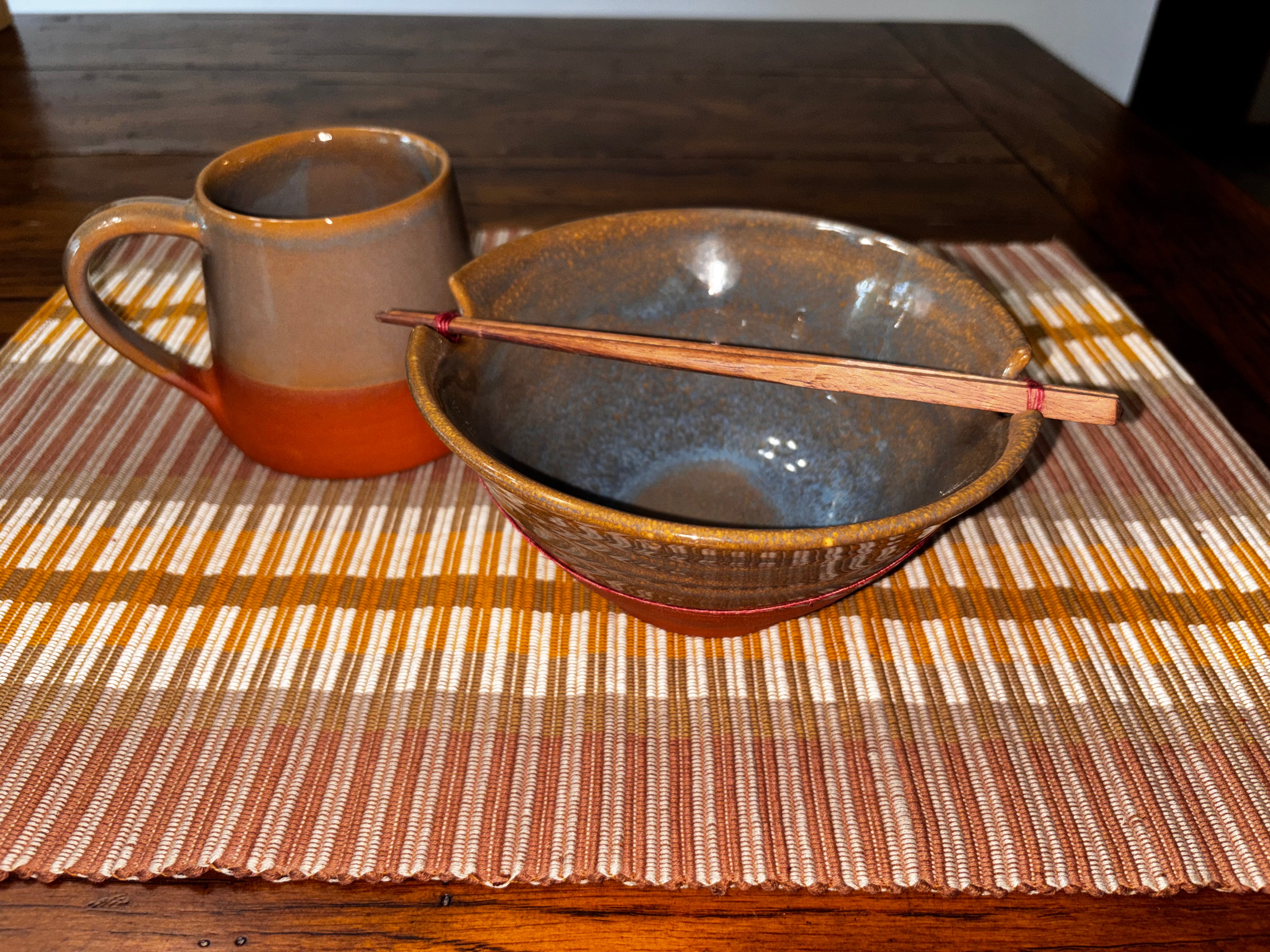 Terra Cotta Harvest Ramen Set — terra cotta ceramic mug, stoneware bowl with chopsticks, and brown striped handloomed placemat, handcrafted in Nepal by Ten Thousand Villages