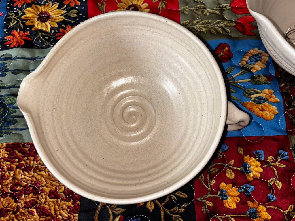 "Overhead view of Gravesco handmade cream ceramic mixing bowl showing spiral center detail, pour spout, and ribbed texture"